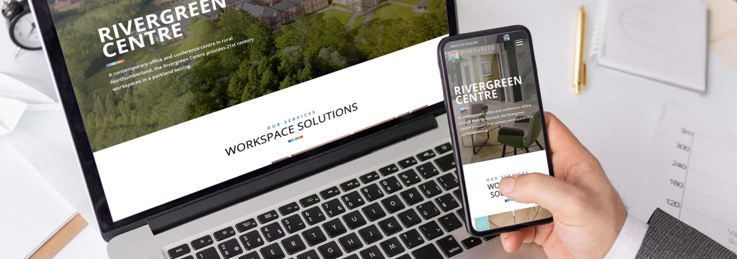 person holding phone with infront of laptop, looking at Rivergeen Centre website