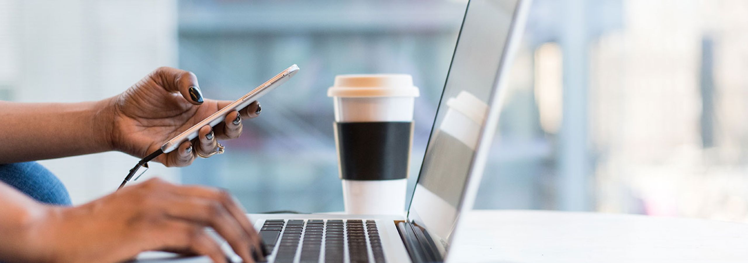 person looking at mobile and working on a laptop