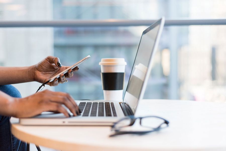 person looking at mobile and working on a laptop